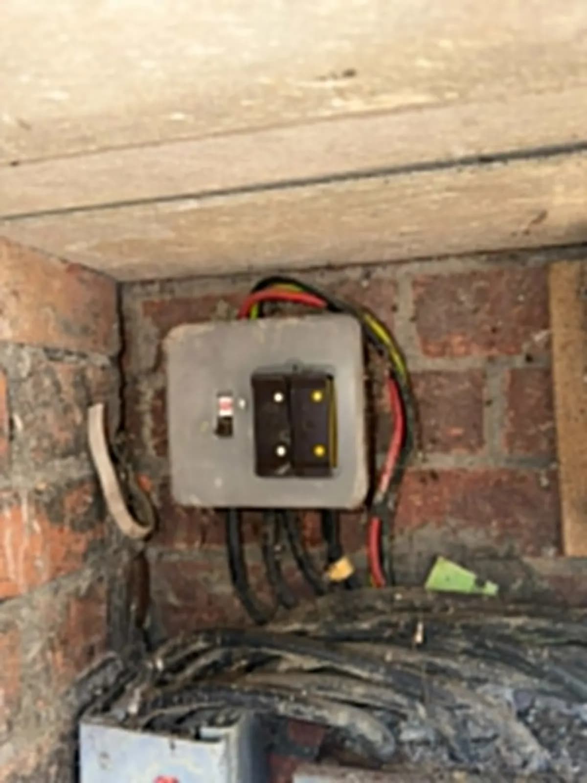 Old fuse board with exposed wiring in a brick meter cupboard in Redhill, before the upgrade