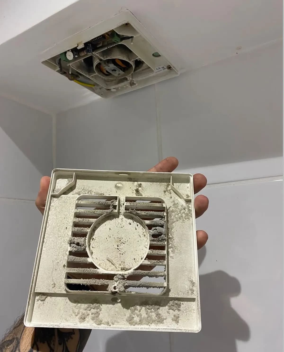 Old, clogged bathroom extractor fan cover removed from the ceiling in Redhill